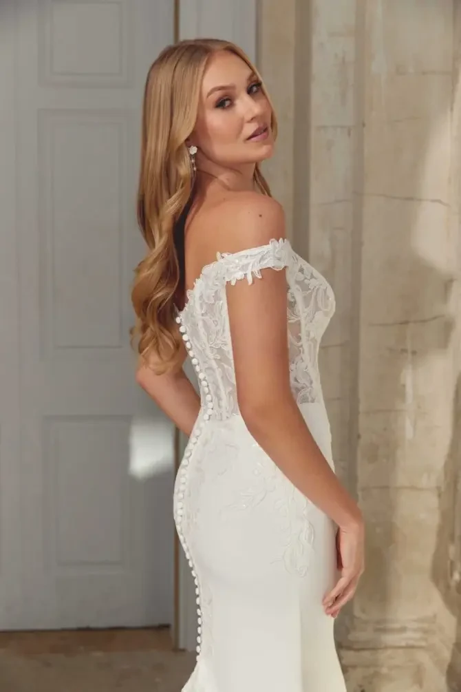 model is wearing an off the shoulder fit and flare wedding dress