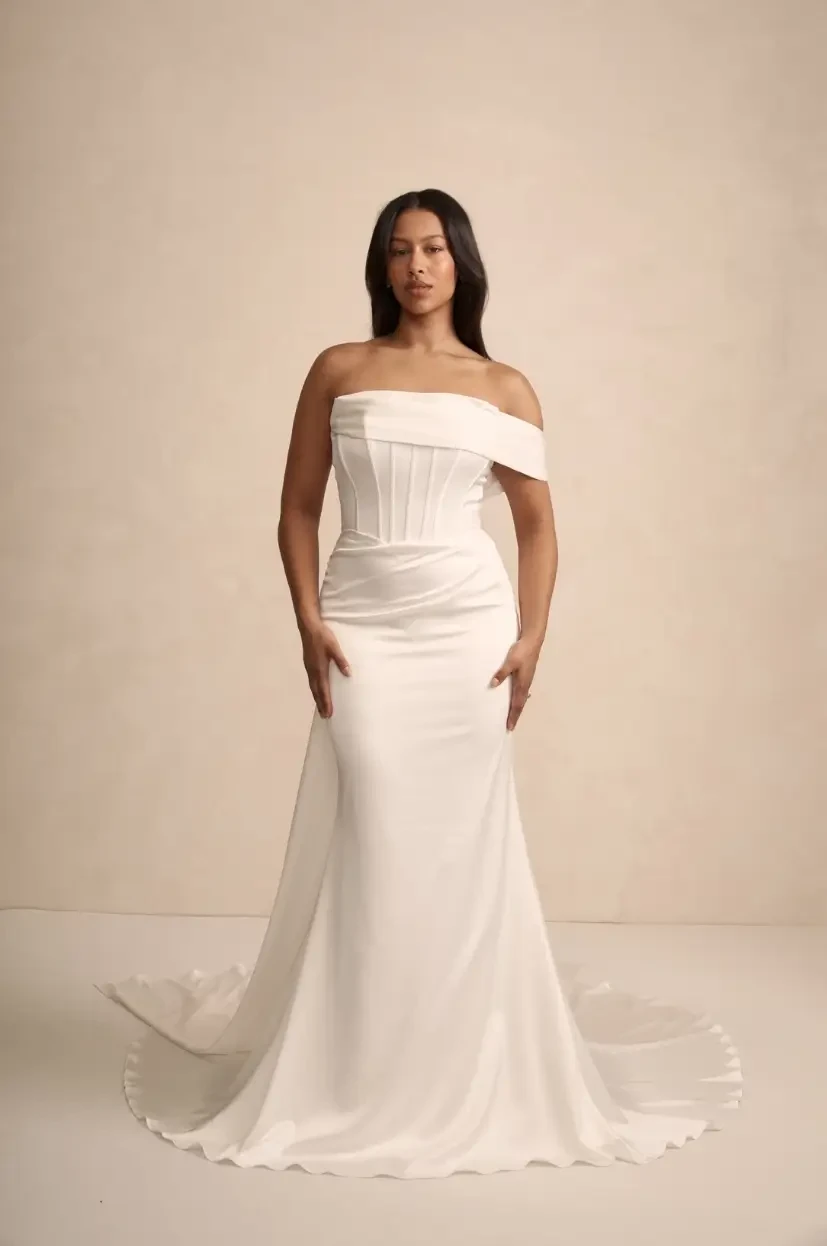 model is wearing an off the shoulder fitted bridal gown