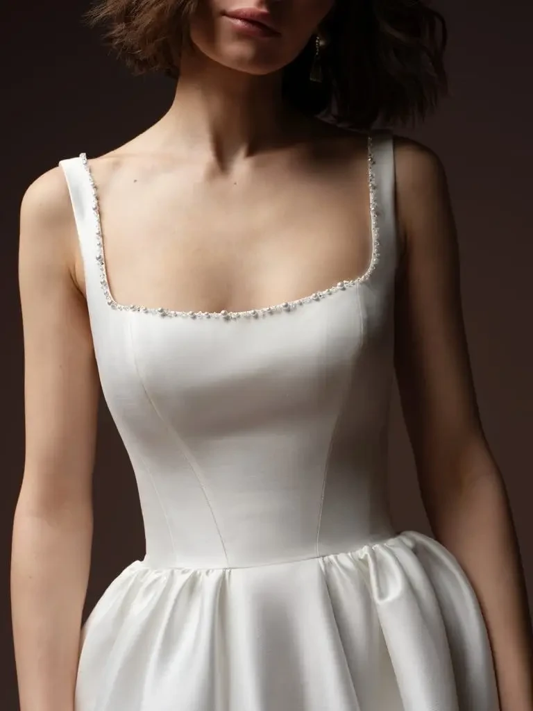A model wearing a classic white wedding dress with a fitted bodice and a full skirt, paired with a long veil.